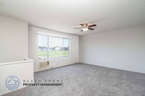 an empty living room with a ceiling fan and a window